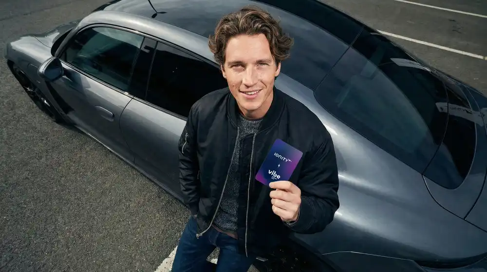 Originales vibe-Motiv: Mann mit IONITY-vibe-Ladekarte neben einem grauen E-Auto